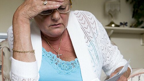 Woman looking concerned while reading a piece of paper